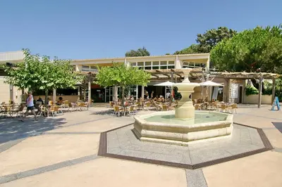 a fountain in the middle of a courtyard with tables and chairs at Residence Club Marina Viva in Porticcio