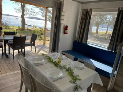 a kitchen with white cabinets and a table with chairs at Camping La Baie des Voiles in Porto-Vecchio