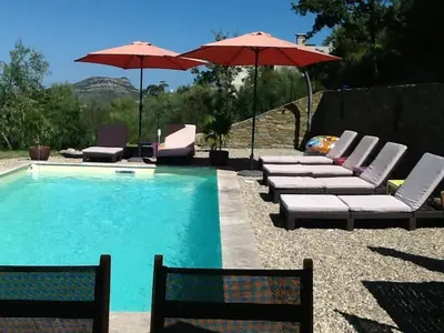 a pool with lounge chairs and umbrellas next to it at U Muzzelo in Oletta