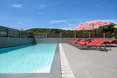 a swimming pool with red chairs and an umbrella at Le Golfe in Porto Pollo