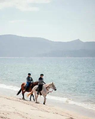 two people riding horses on the beach at Le Golfe in Porto Pollo