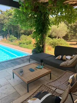 a living room with a couch and a table next to a pool at Villa SoleLuna chambre Jeanne in Bonifacio