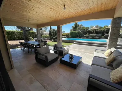 a patio with a couch and chairs and a table at villa standing piscine chauffée privée in Sainte-Lucie de Porto-Vecchio