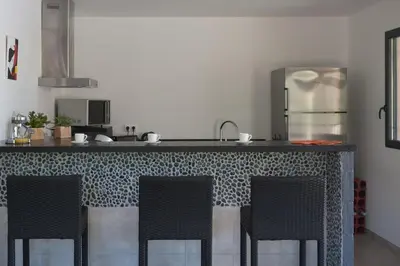 a kitchen with a counter with four chairs around it at villa standing piscine chauffée privée in Sainte-Lucie de Porto-Vecchio