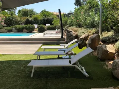 a row of lounge chairs sitting next to a pool at villa standing piscine chauffée privée in Sainte-Lucie de Porto-Vecchio