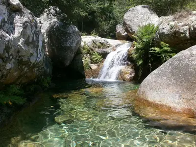 a waterfall in a pool of water with rocks at Casa Petra SALGA in Corte