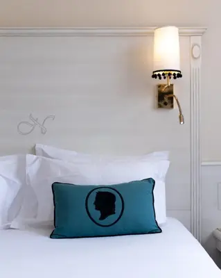 a white bed with a blue pillow on it at Napoleon in Ajaccio