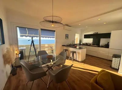 a living room with a couch and a table and a kitchen at Magnifique appartement vue mer, spacieux et traversant in Ajaccio
