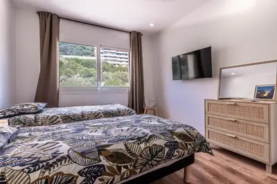 a bedroom with a bed and a dresser with a television at Magnifique appartement vue mer, spacieux et traversant in Ajaccio