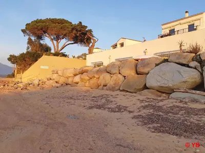 a rock retaining wall next to a building at Un balcon sur la mer - Duplex 60 m2 - Chambres à l'étage - Pieds dans l'eau - Accès plage sans route à traverser in Porticcio