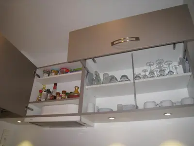 a cupboard with dishes and other items in it at Un balcon sur la mer - Duplex 60 m2 - Chambres à l'étage - Pieds dans l'eau - Accès plage sans route à traverser in Porticcio
