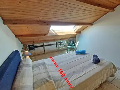 a large bed in a room with a wooden ceiling at Un balcon sur la mer - Duplex 60 m2 - Chambres à l'étage - Pieds dans l'eau - Accès plage sans route à traverser in Porticcio
