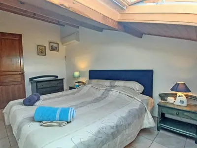 a bedroom with a large bed with a blue headboard at Un balcon sur la mer - Duplex 60 m2 - Chambres à l'étage - Pieds dans l'eau - Accès plage sans route à traverser in Porticcio