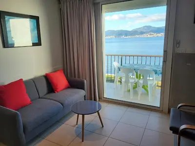a living room with a couch and a view of the ocean at Un balcon sur la mer - Duplex 60 m2 - Chambres à l'étage - Pieds dans l'eau - Accès plage sans route à traverser in Porticcio