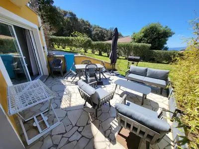 a patio with chairs and tables and an umbrella at T3 Propriano vue mer, neuf, climatisé et classé 4 étoiles in Viggianello
