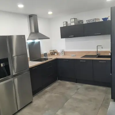 a kitchen with black cabinets and a stainless steel refrigerator at T3 Propriano vue mer, neuf, climatisé et classé 4 étoiles in Viggianello