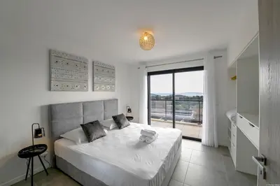 a white bedroom with a large bed and a window at Villa neuve et luxueuse vue mer proche Portovecchio in Zonza