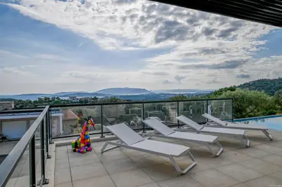 a balcony with white chairs and a swimming pool at Villa neuve et luxueuse vue mer proche Portovecchio in Zonza