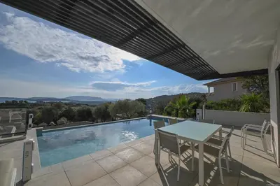 a patio with a table and chairs and a swimming pool at Villa neuve et luxueuse vue mer proche Portovecchio in Zonza