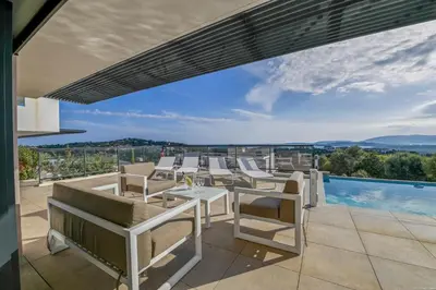 a patio with white chairs and a swimming pool at Villa neuve et luxueuse vue mer proche Portovecchio in Zonza
