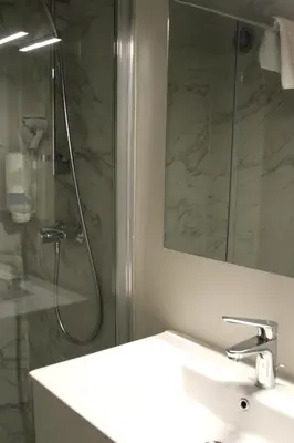 a bathroom with a sink and a shower with a mirror at Hôtel Albion in Ajaccio
