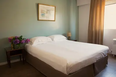 a bedroom with a large bed with white sheets and pillows at Hôtel Albion in Ajaccio
