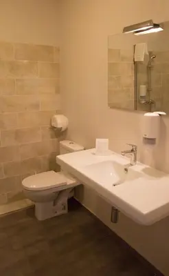 a bathroom with a sink and a toilet and a mirror at Hôtel Albion in Ajaccio