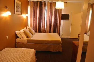 a hotel room with two beds and a window at Hôtel Albion in Ajaccio