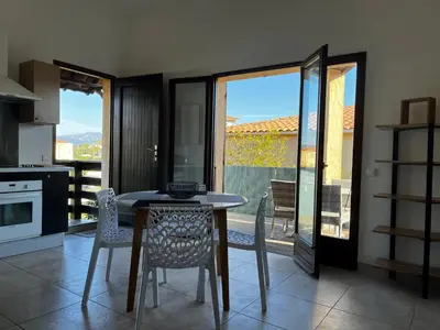 a kitchen with a table and chairs and a balcony at Résidence Mare Bellu Agosta plage in Porticcio