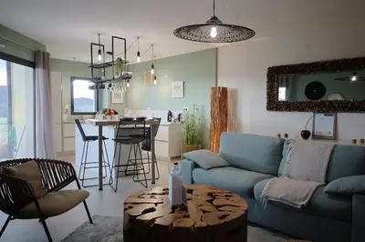 a living room with a blue couch and a kitchen at I Salini - T3 élégant & calme près du centre - Classé 4 étoiles in Porto-Vecchio