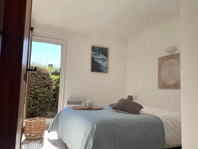 a white bedroom with a bed and a window at Villa Bougainville in Porticcio