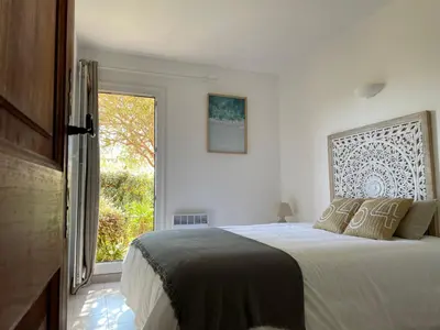 a white bedroom with a bed and a window at Villa Bougainville in Porticcio