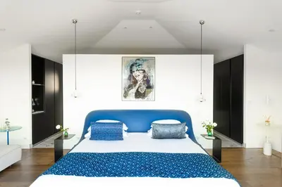 a bedroom with a blue bed and white walls at Hôtel Version Maquis Santa Manza in Bonifacio