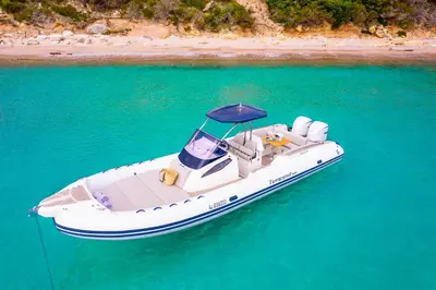 a white boat floating in the water near a beach at Hôtel Version Maquis Santa Manza in Bonifacio