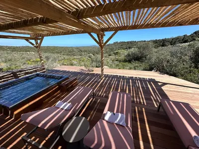 a deck with purple chairs and a hot tub at Hôtel Version Maquis Santa Manza in Bonifacio