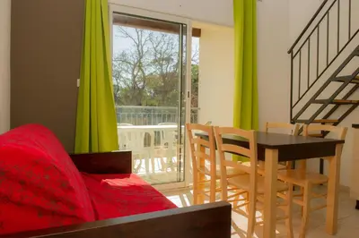 a living room with a table and chairs and a couch at Résidence Goélia Perla D'Isula in Linguizzetta