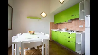 a kitchen with green cabinets and a white table at Air-conditioned apartment near Porto Vecchio, 500 m sea, 8 people, two bathrooms in Zonza