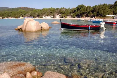 a boat sitting in the water next to some rocks at Air-conditioned apartment near Porto Vecchio, 500 m sea, 8 people, two bathrooms in Zonza