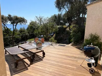 a deck with two picnic tables and a grill at Ogliastrello in Olmeto