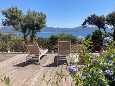 two chairs on a deck with a view of the water at Ogliastrello in Olmeto