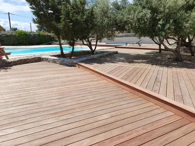 a wooden deck next to a swimming pool with trees at Résidence Canava in Bonifacio