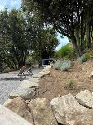 a bench in a park with rocks and trees at A Casa Vadiiolina - Chambres d'hôtes d'exception in Sollacaro