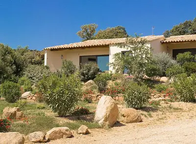 a house with rocks in front of a yard at Résidence A Rundinella in Porto-Vecchio
