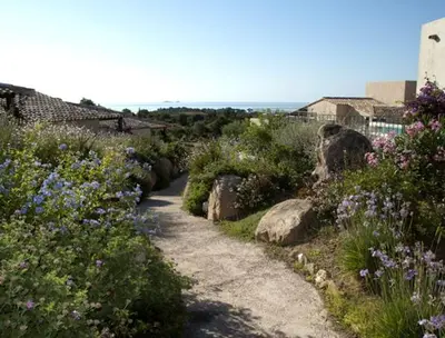 a path through a garden with flowers and rocks at Résidence A Rundinella in Porto-Vecchio