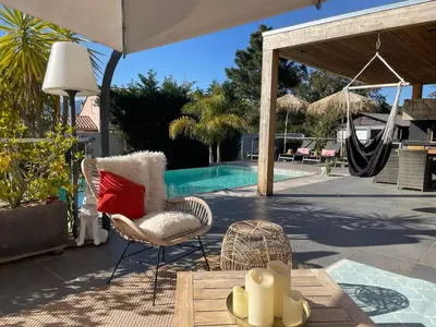 a patio with a chair and a hammock next to a pool at Villa CASA BAGGIA, proche plage, piscine à débordement chauffée, pool house in Porto-Vecchio