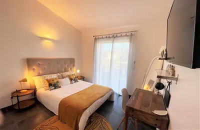 a bedroom with a bed and a table and a window at Villa CASA BAGGIA, proche plage, piscine à débordement chauffée, pool house in Porto-Vecchio