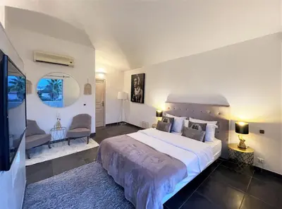 a large bedroom with a large bed and a living room at Villa CASA BAGGIA, proche plage, piscine à débordement chauffée, pool house in Porto-Vecchio