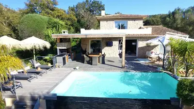 a house with a swimming pool in front of a house at Villa CASA BAGGIA, proche plage, piscine à débordement chauffée, pool house in Porto-Vecchio