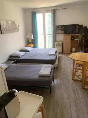 a room with two beds and a table and a tv at AJACCIO / CENTRE VILLE / PORT 2mn / PARKING PROCHE/ TOUTES COMMODITES in Ajaccio
