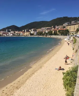 a beach with people laying on the sand and the water at AJACCIO / CENTRE VILLE / PORT 2mn / PARKING PROCHE/ TOUTES COMMODITES in Ajaccio